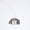 Sterling silver necklace featuring a hand-painted ceramic pendant with a playful straight-haired face design, displayed on a white background.