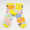 Front view of the sunny bunch socks. This vibrant design features hand-drawn flowers in bright, cheerful hues, blooming in shades of yellow, orange, pink, and blue. Happy and warm smiles peek through the design, reminding you to embrace joy in every season. With a sunny yellow cuff, heel, and toe, these socks bring a warm, uplifting energy to any outfit.
