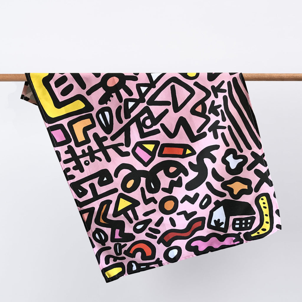 The sweet tea towel hanging from a rack. Abstract, and geometric lines and shapes, on a pink background. 