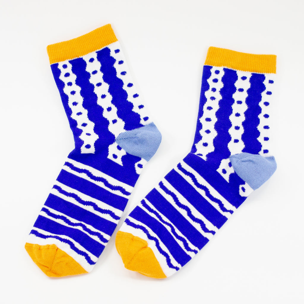 Picture of the TENGU socks side by side. Featuring a bold blue and white pattern of playful waves, dots, and stripes, these socks bring energy and excitement to every step. The bright yellow cuff and toe add a pop of colour, while the soft blue heel keeps things stylish and unique.
