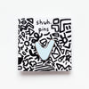 Small enamel pin with a stylised V shape, as though its arms are raised in celebration, displayed on white card with illustrated squiggles and “shuh. pins” branding.