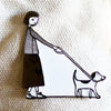 Enamel pin featuring a hand-drawn person and dog walking side-by-side in matching poses