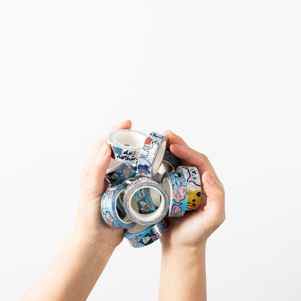 A picture of two hands holding the entire collection of shuh. washi tapes. 