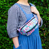 The wave bumbag being carried across the shoulder. Pattern features wavy multicoloured lines on a black background. 