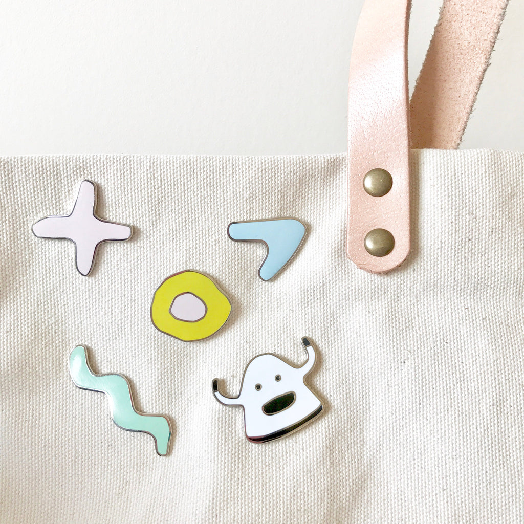 collection of shuh. pins on a bag. Including a monster, and various shapes. 